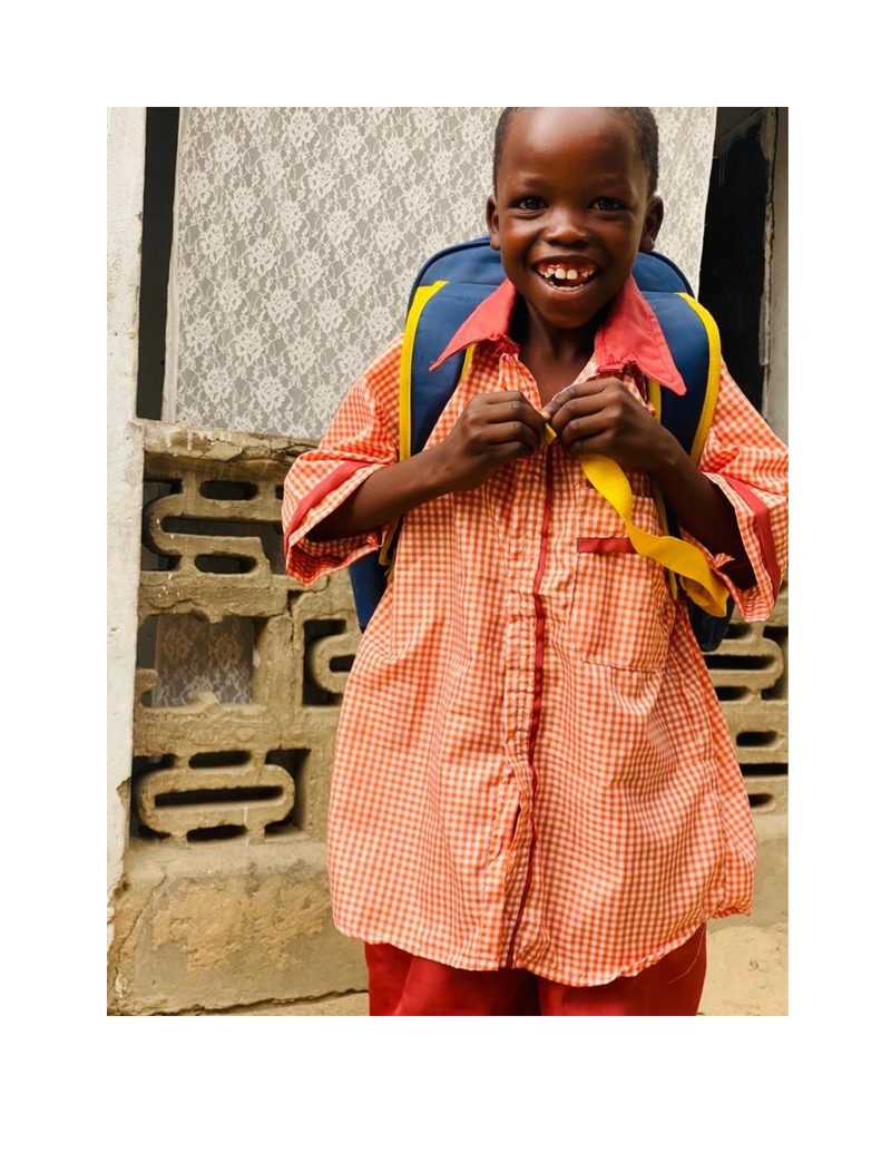 Ahmad Usman laughing broadly in his orange school uniform with a navy and yellow backpack
