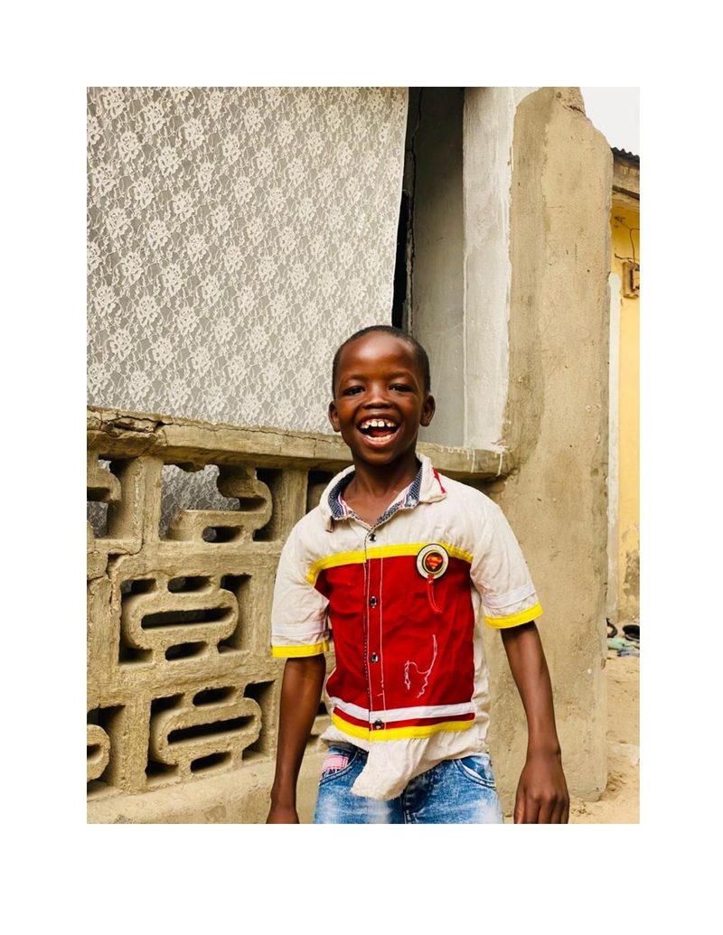 Ahmad before receiving his uniform, wearing casual clothes and a Superman badge, laughing outdoors