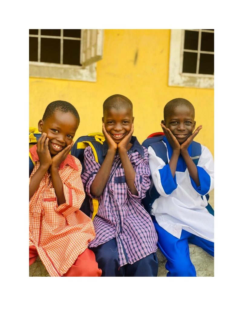 Mohammed Ali sitting in the middle of two friends, all three laughing with hands on their cheeks
