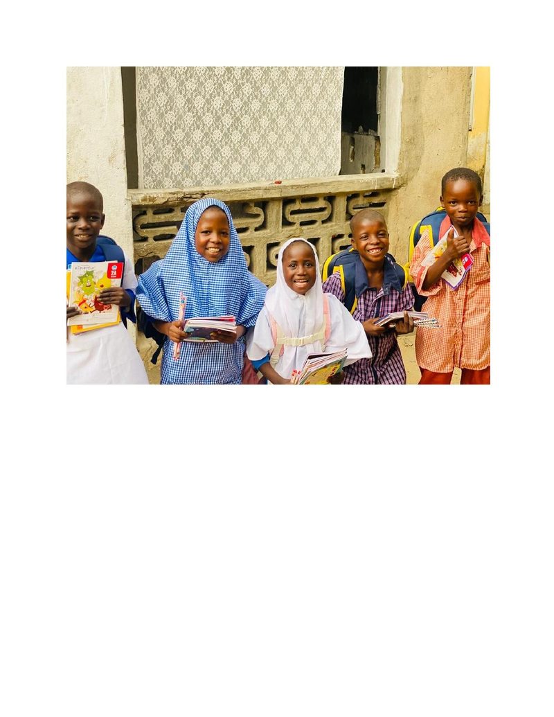 Children in school uniforms holding up new books and school bags