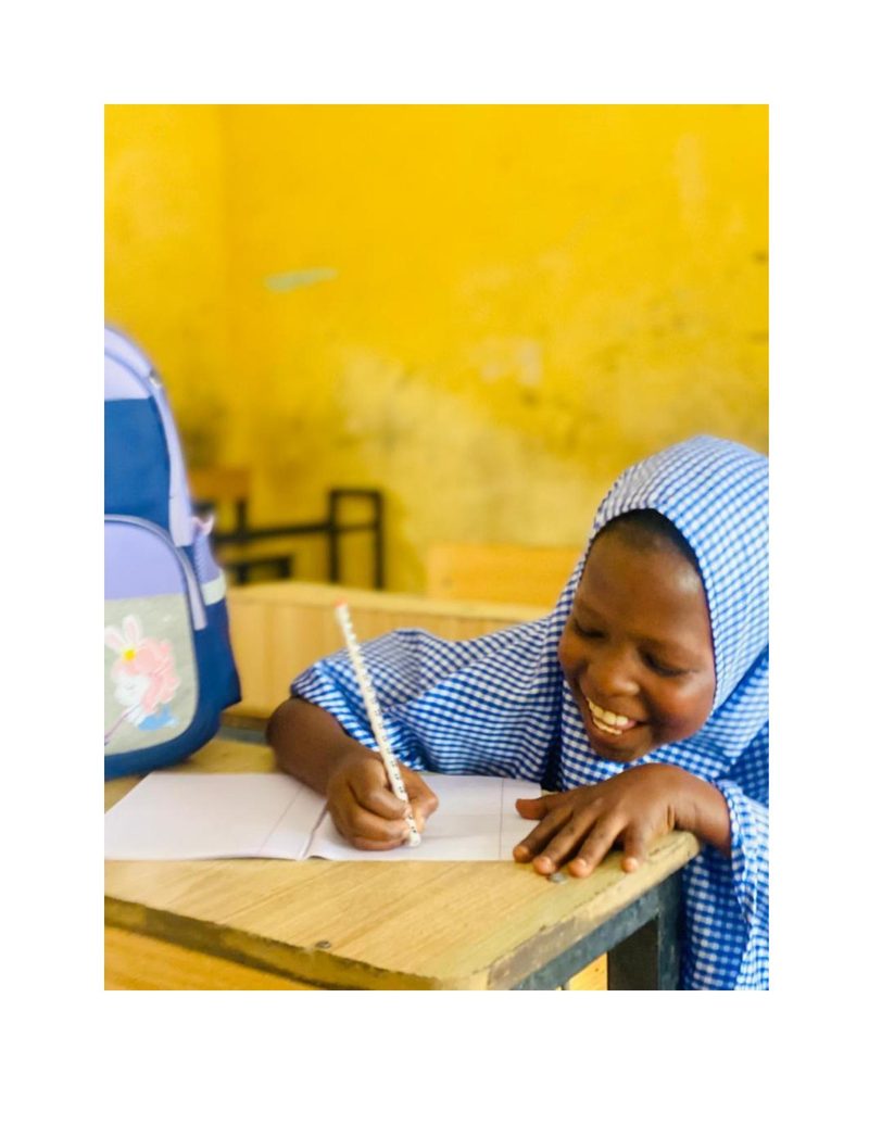 Close-up of Bilkisu focused on her notebook, smiling down at her work