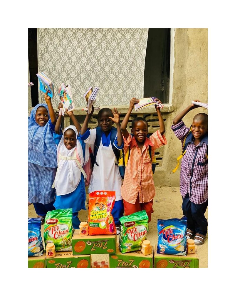 Group of children celebrating with arms raised holding books and school supplies