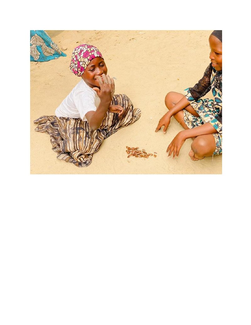 Close-up of Fatima and her friend focused on their seed game, one laughing