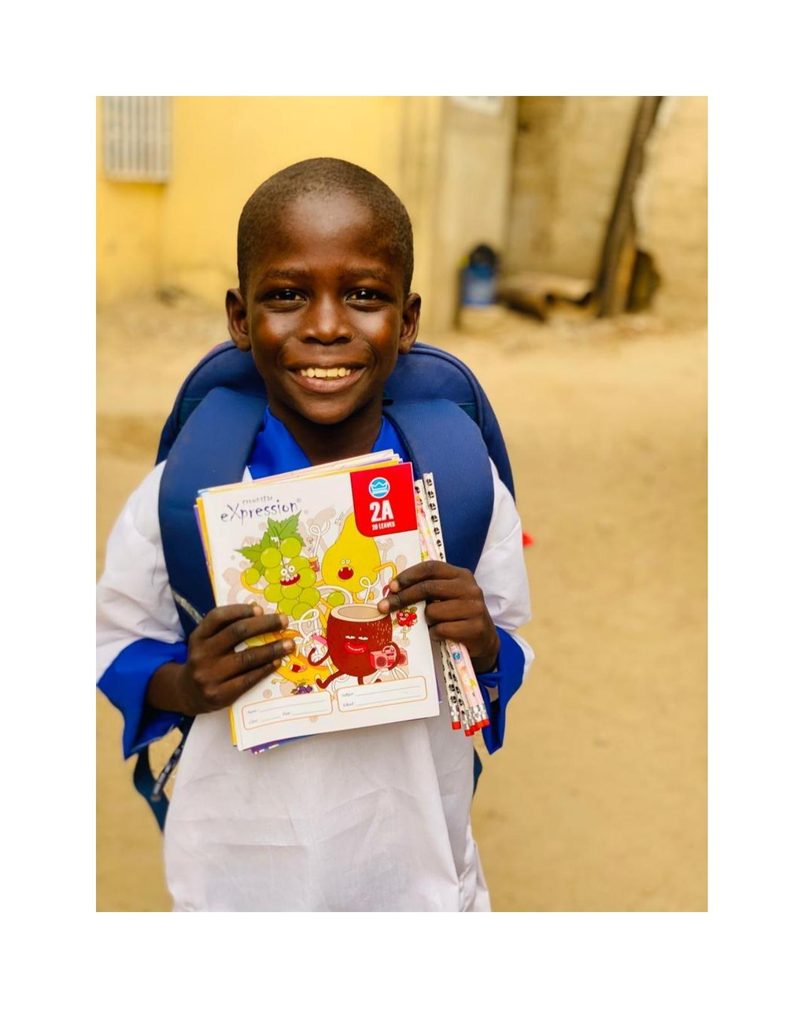 Musa Mohammed holding his new notebooks with a wide smile