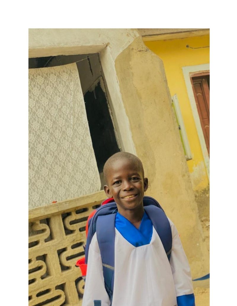 Musa Mohammed in his new school uniform smiling proudly outside his home